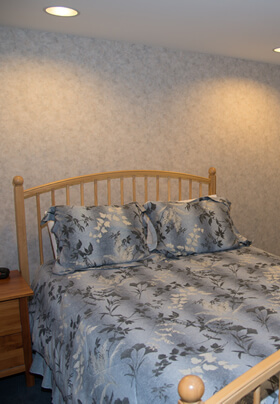Bedroom with light colored maple bed frame and dresser with mirror.