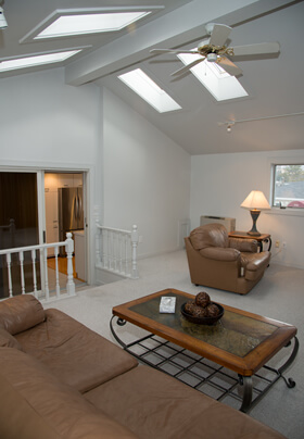 Lovely, spacious living room with white carpet and tan leather furniture.