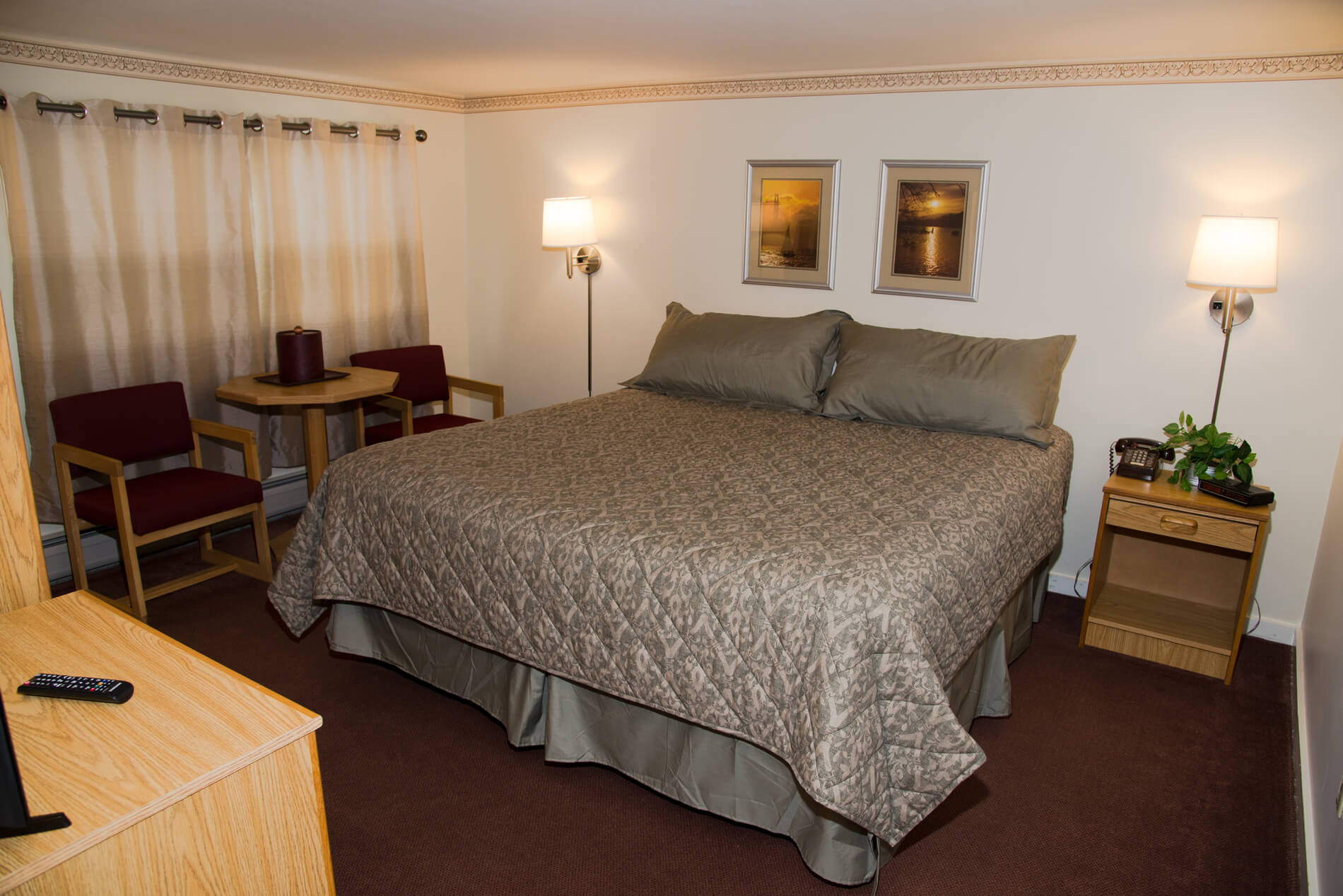 A room in the Inn with a large King sixe bed showing table and maroon chairs.