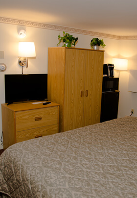 Deluxe room with King bed with green bedspread and flat screen TV.