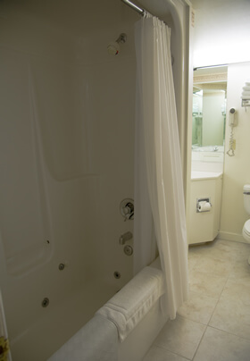 Spacious bathroom in white showing shower and sparling clean white tile.