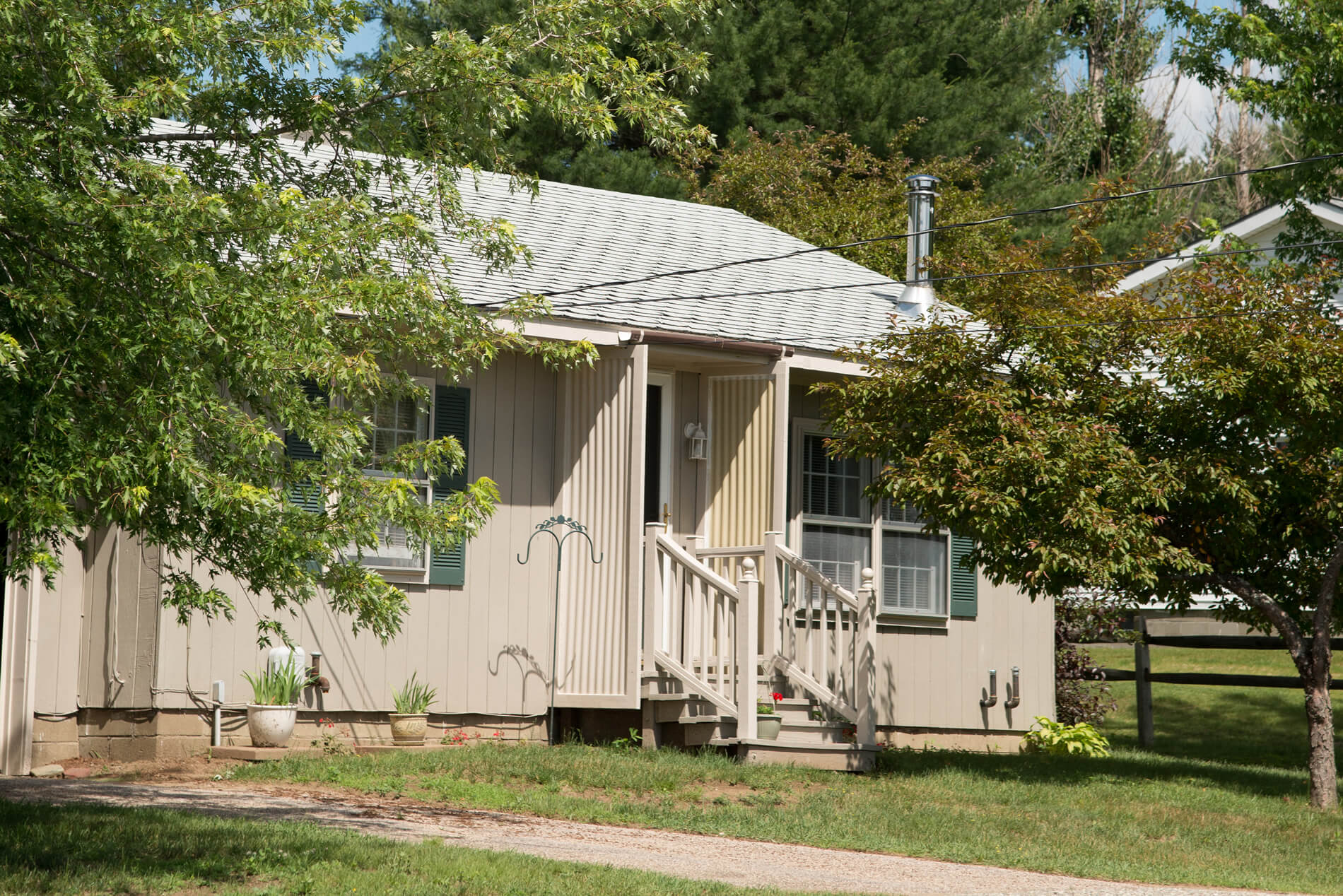 View of large lawn and two houses. One house is light green. One house is white.